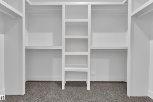 Custom closet system featuring white shelving, hanging rods, and built-in vertical storage - 247 Linden Loop, Leduc, AB - Indoor With Storage