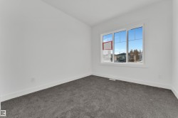 Room featuring a large white-framed window, neutral white walls, and dark grey carpet flooring - 