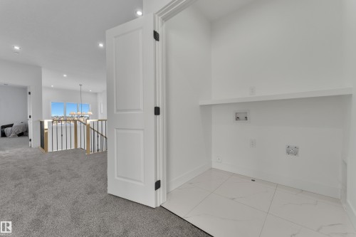 Dedicated laundry area featuring white tile flooring, a built-in shelf, and essential utility hookups - 247 Linden Loop, Leduc, AB - Indoor Photo Showing Other Room