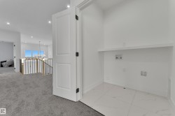Dedicated laundry area featuring white tile flooring, a built-in shelf, and essential utility hookups - 