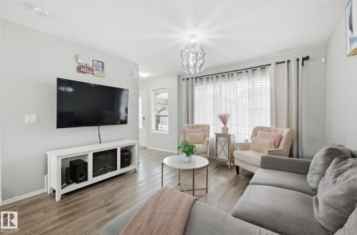 This living area features light-colored walls and wood-look flooring - 4636 175 Ave, Edmonton, AB - Indoor Photo Showing Living Room