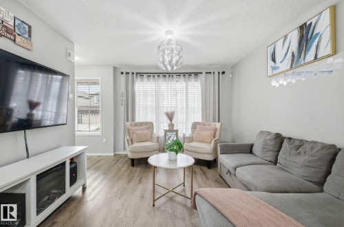 Living area featuring light gray walls, wood-style flooring, and a window with blinds and curtains - 4636 175 Ave, Edmonton, AB - Indoor Photo Showing Living Room With Fireplace