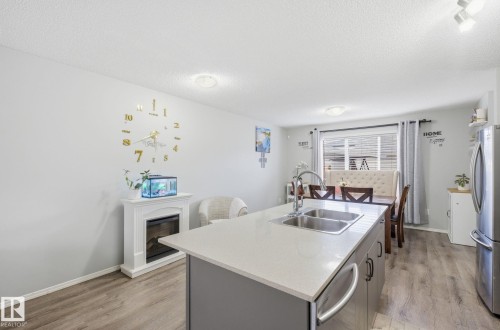 The property features an open-concept living area with light-colored walls and wood-look flooring - 4636 175 Ave, Edmonton, AB - Indoor Photo Showing Kitchen With Double Sink