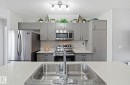 The kitchen features modern gray cabinetry, stainless steel appliances, a white hexagonal tile backsplash, and a large sink with a chrome faucet - 4636 175 Ave, Edmonton, AB  - Indoor Photo Showing Kitchen With Double Sink With Upgraded Kitchen 