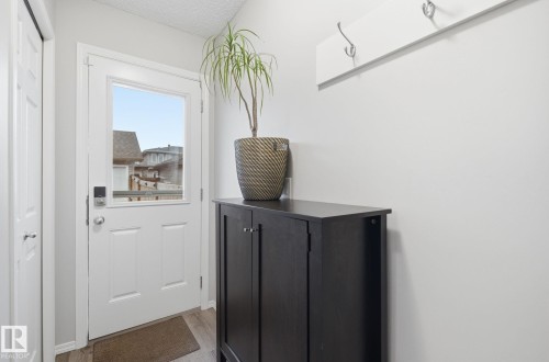 Entryway featuring a white door with a window, light-colored walls, and a coat rack with hooks - 4636 175 Ave, Edmonton, AB - Indoor Photo Showing Other Room