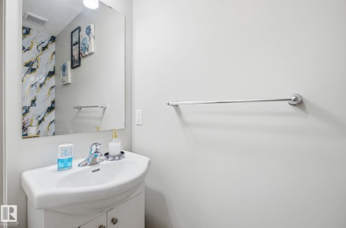 Bathroom featuring a white vanity with a ceramic sink and a chrome faucet, set against light-colored walls - 4636 175 Ave, Edmonton, AB - Indoor Photo Showing Bathroom
