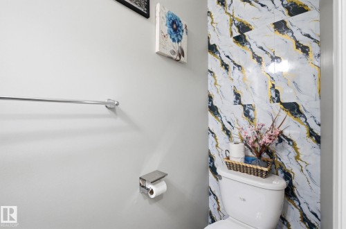 Bathroom featuring a toilet with striking marble-patterned wall tiles behind it - 4636 175 Ave, Edmonton, AB - Indoor Photo Showing Bathroom