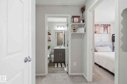 This property features a well-appointed bathroom with a vanity and mirror, and a bedroom with a bed and a headboard - 4636 175 Ave, Edmonton, AB - Indoor