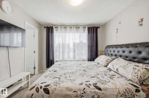 This bedroom features a window with blinds and dark curtains, light-colored walls, and a textured ceiling - 4636 175 Ave, Edmonton, AB - Indoor Photo Showing Bedroom