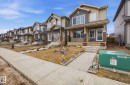The property features a two-story exterior with a mix of siding and stone accents, a covered front porch with railings, and a concrete pathway leading to the entrance - 4636 175 Ave, Edmonton, AB  - Outdoor With Facade 