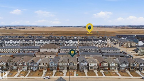 Aerial view of the community, showcasing a mix of detached properties and townhouses, with a large open field visible in the background - 4636 175 Ave, Edmonton, AB - Outdoor With View