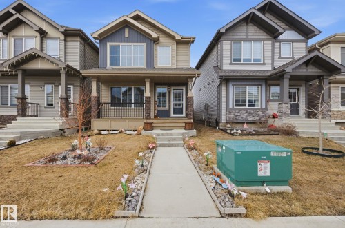 The property features a two-story exterior with a porch, a front walkway, and a small landscaped area with rocks and decorative flowers - 4636 175 Ave, Edmonton, AB - Outdoor With Facade