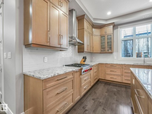 Spacious kitchen featuring light wood cabinetry with brushed nickel hardware, white subway tile backsplash, and granite countertops - 8927 120 Street, Edmonton, AB - Indoor Photo Showing Kitchen With Upgraded Kitchen