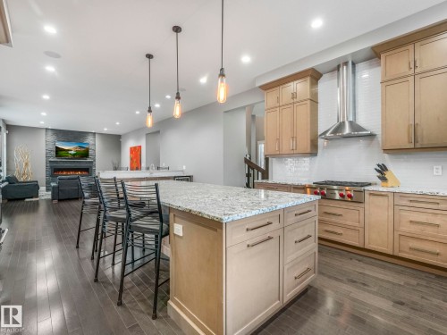 Gourmet kitchen featuring a large island with stone countertop, stainless steel range with hood, custom cabinetry, and subway tile backsplash - 8927 120 Street, Edmonton, AB - Indoor Photo Showing Kitchen With Upgraded Kitchen