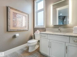 Contemporary bathroom featuring a white vanity with polished chrome hardware, a gray speckled countertop, and a tiled backsplash - 