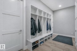 Mudroom featuring extensive built-in white cabinetry with individual storage cubbies and coat hooks - 