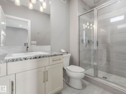 Bathroom featuring a white vanity with slab cabinet doors, a granite-finish countertop, and an undermount sink - 