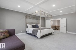 Spacious room featuring coffered ceilings with recessed lighting, light-toned carpeting, and a neutral wall palette - 