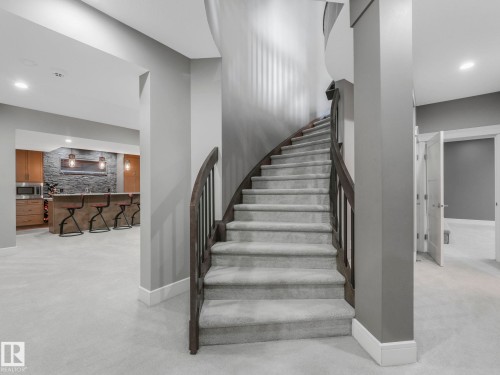 Curved staircase with wood-finish handrail and carpeted steps - 8927 120 Street, Edmonton, AB - Indoor Photo Showing Other Room