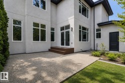 Modern exterior featuring a light gray stucco finish, multiple white-framed windows, and a black trim roofline - 
