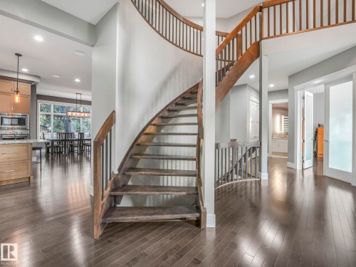 Curved staircase featuring dark wood treads and railings, complemented by hardwood flooring throughout - 8927 120 Street, Edmonton, AB - Indoor Photo Showing Other Room