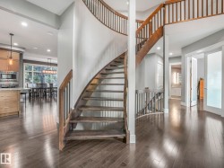 Curved staircase featuring dark wood treads and railings, complemented by hardwood flooring throughout - 