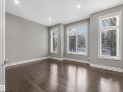 Spacious room featuring rich wood-finish flooring, recessed lighting, expansive windows with integrated blinds, crisp white trim, and a contemporary light gray wall finish - 