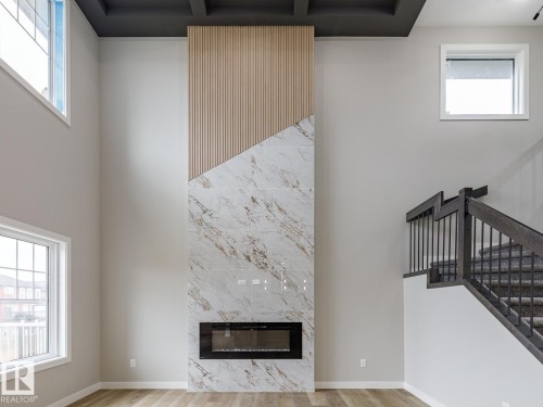 Two-story living area featuring a full-height fireplace with a linear insert and a white and gold veined finish - 48 Chartres Close, St. Albert, AB - Indoor With Fireplace