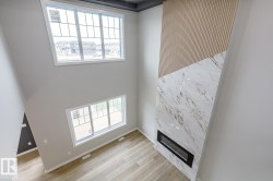 High ceilings featuring a two-story accent wall with wood paneling and a large-format tile surround - 