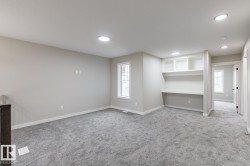 Spacious room featuring light gray carpeting, recessed lighting, and a built-in desk with shelving - 