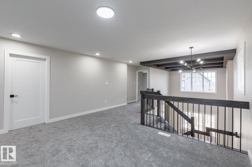 Upper-level landing featuring textured gray carpeting, recessed ceiling lighting, and a modern black chandelier - 48 Chartres Close, St. Albert, AB - Indoor Photo Showing Other Room