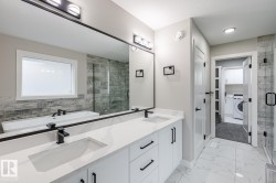 Bathroom featuring a dual vanity with white cabinetry, integrated sinks, and black hardware - 