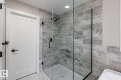 Walk-in shower featuring a glass enclosure, wood-finish tile surround, and matte black fixtures - 