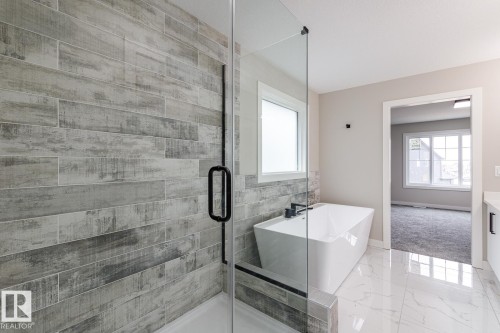 Modern bathroom featuring a frameless glass shower enclosure and a freestanding soaking tub with a wall-mounted faucet - 48 Chartres Close, St. Albert, AB - Indoor Photo Showing Bathroom