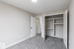 Neutral-toned room featuring a built-in closet with shelving and hanging rods - 