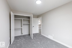 Interior room featuring neutral wall paint, gray carpeting, a built-in closet with double doors and shelving, and a flush-mount ceiling light fixture - 