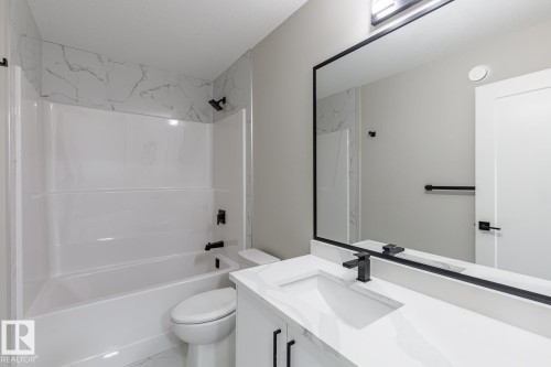 Bathroom featuring a white vanity with an integrated sink, black faucet, and a large framed mirror - 48 Chartres Close, St. Albert, AB - Indoor Photo Showing Bathroom