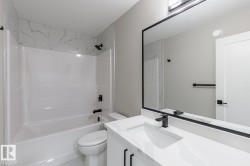 Bathroom featuring a white vanity with an integrated sink, black faucet, and a large framed mirror - 