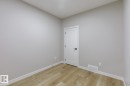 Neutral-toned room featuring light wood-finish flooring, white baseboards, and a contemporary white door with matte black hardware - 48 Chartres Close, St. Albert, AB  - Indoor Photo Showing Other Room 