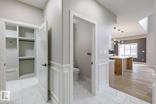 Entryway featuring white marble-look tile flooring and wainscoting, with a built-in closet system - 48 Chartres Close, St. Albert, AB - Indoor Photo Showing Other Room