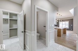 Entryway featuring white marble-look tile flooring and wainscoting, with a built-in closet system - 