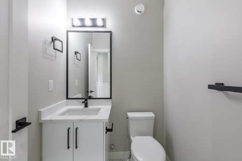 Bathroom featuring a modern vanity with a white countertop and integrated sink, matte black faucet, and a rectangular mirror with a black frame - 48 Chartres Close, St. Albert, AB - Indoor Photo Showing Bathroom