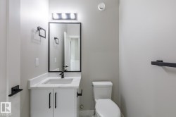 Bathroom featuring a modern vanity with a white countertop and integrated sink, matte black faucet, and a rectangular mirror with a black frame - 