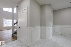 Entryway featuring white wainscoting and marble-look flooring - 