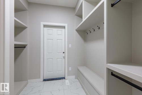 Mudroom featuring built-in shelving, a storage bench, and a six-panel entry door - 48 Chartres Close, St. Albert, AB - Indoor