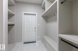 Mudroom featuring built-in shelving, a storage bench, and a six-panel entry door - 