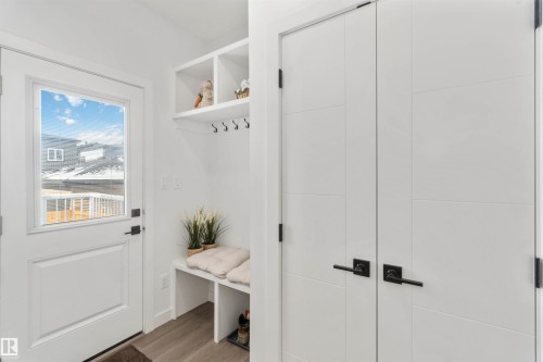 Entryway mudroom featuring built-in shelving, coat hooks, and a bench with shoe storage - 124 28 Street, Edmonton, AB 