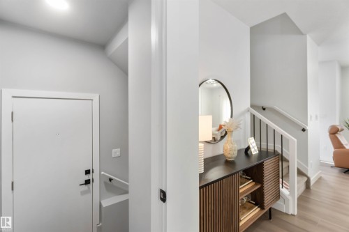 Entryway featuring a solid panel door with matte black hardware, recessed lighting, and a contemporary wood-finish console with reeded details - 124 28 Street, Edmonton, AB 