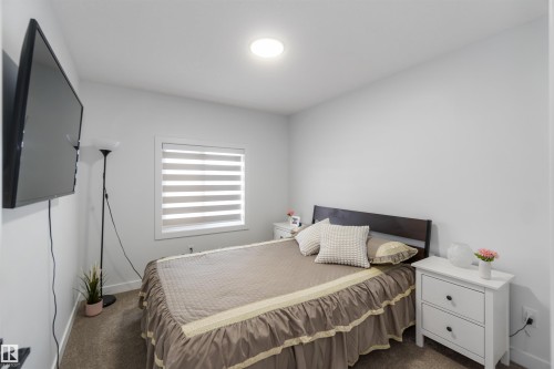 Bedroom featuring neutral wall paint, carpet flooring, a window with layered blinds, and a ceiling-mounted light fixture - 124 28 Street, Edmonton, AB 