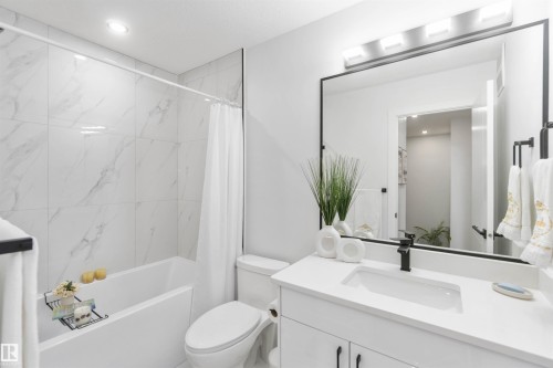 Modern bathroom featuring a white vanity with integrated sink and matte black faucet - 124 28 Street, Edmonton, AB 